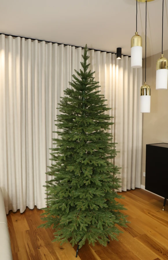 Choinka sztuczna Świerk Naturalny Szczupły 100% PE 220 cm. Sztuczne drzewko Świerk Naturalny Szczupły. Drzewko świąteczne Świerk Naturalny Szczupły. Choinka sztuczna jak Żywa. Zdjęcie choinki w całym rozmiarze na tle przestronnego okna salonowego.
